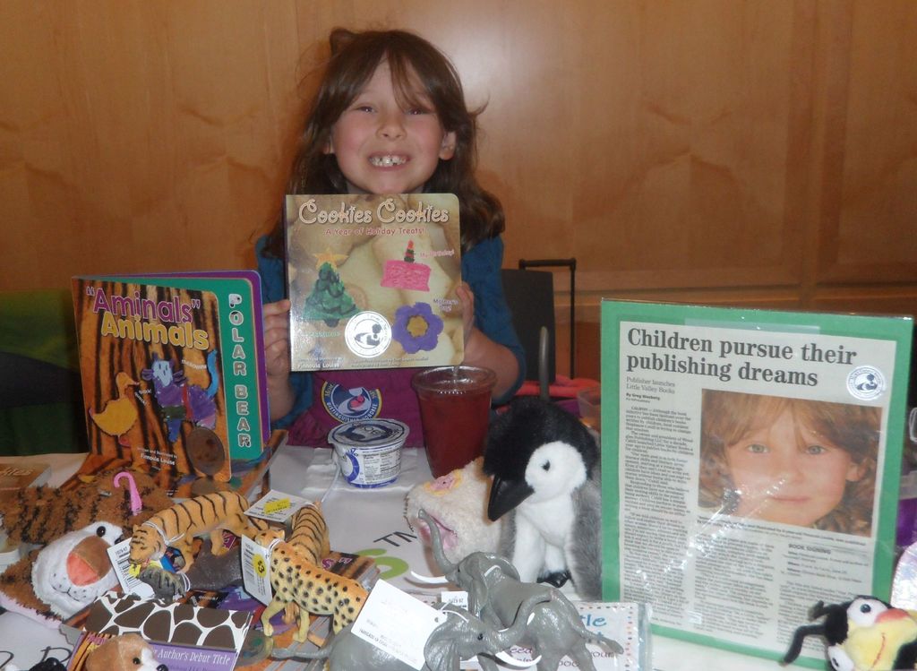 Ein kleines Mädchen hält eine Keksdose in der Hand und steht vor Spielzeug und Büchern.