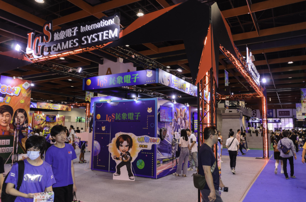 Eine Gruppe von Menschen, die durch einen Veranstaltungsraum auf einer Gaming-Messe in China gehen, mit Taschen und Gegenständen in den Händen, Text- und Bildtafeln, Deckenbeleuchtung und Teppichboden.
