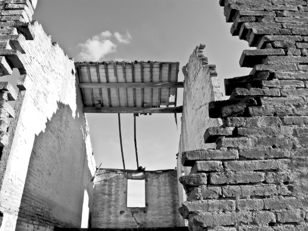 Ein altes Gebäude mit Wänden unter einem Himmel, dargestellt in Schwarz-Weiß.