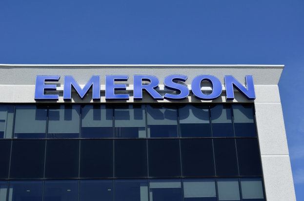 The Emerson logo on the side of a building with text stating "Emerson to invest $1.5 billion in the US" against a clear blue sky.