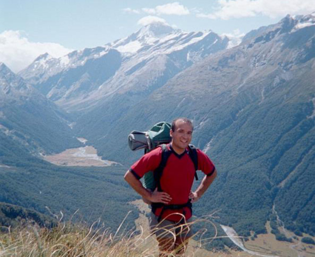 Eine Person mit Rucksack steht vor Bergen