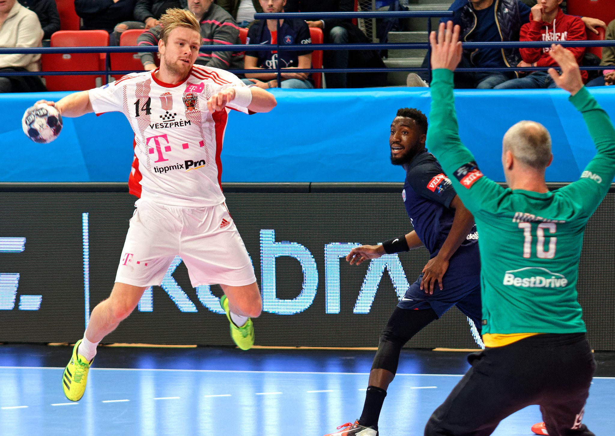 A group of men playing handball on a court during the Futsal World Cup 2019 match between Bayern Munich and Paris Saint-Germain, with spectators in the background.
