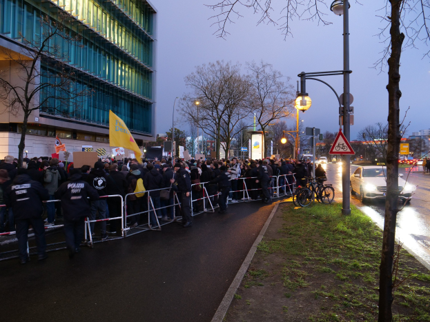 Eine große Gruppe von Menschen protestiert vor einem Gebäude in Berlin und hält Schilder mit Barrikaden und Fahrrädern in der Nähe.