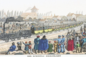 Eine Gruppe von Menschen steht um einen Zug auf einem Gleis, einige sind im Zug und andere auf dem Boden, in der Nähe von Gebäuden und Bäumen, mit dem Text "Ludwigs-Eisenbahn, der erste Bahnhof Deutschlands" unten.