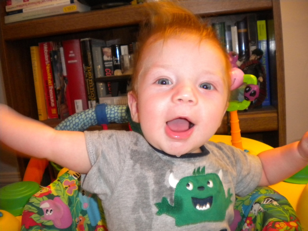 Ein Kind sitzt auf einem Stuhl vor einem Regal mit Büchern, mit einer teilweise sichtbaren Wand im Hintergrund.