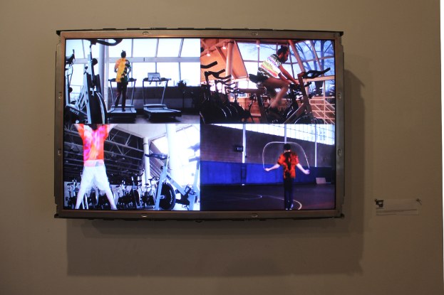 Ein an der Wand montierter Fernseher mit Menschen, die Übungen machen.