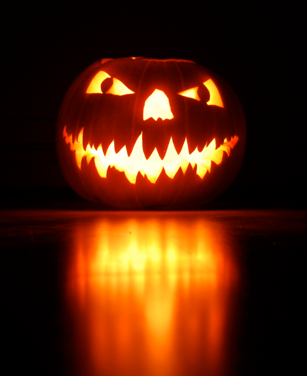 Ein geschnitztes Kürbiskopf sitzt auf dem Boden mit einem dunklen Hintergrund.