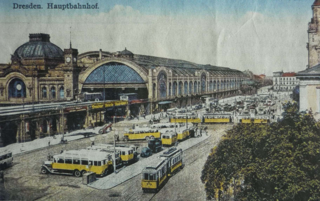 A sepia-toned postcard of Dresden Hauptbahnhof train station in Germany, depicting a busy street scene with vehicles, pedestrians, trees, buildings, and a cloudy sky.