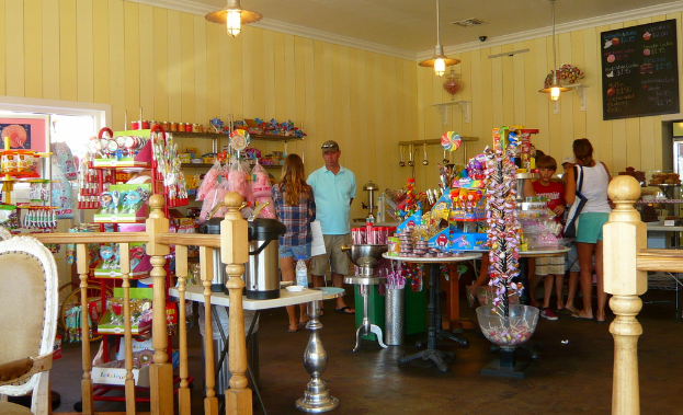 Eine Gruppe von Menschen steht vor einem Geschäft, das Bonbons, Süßigkeiten und Backwaren anbietet.