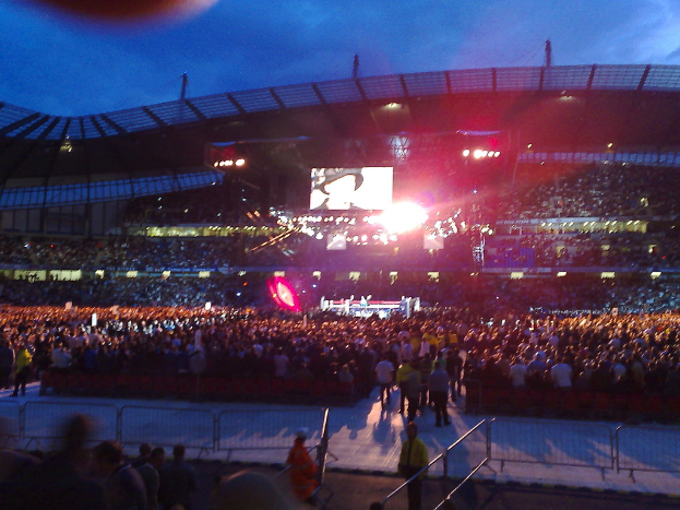 Eine Konzerthalle mit Publikum, Scheinwerfern und einem Projektionsschirm.