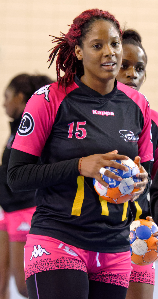 Eine Gruppe von Frauen, die zusammenstehen, jede hält einen Fußball, wobei die Frau in der Mitte ein menschliches Gesicht hat, direkt in die Kamera schaut und eine weiße T-Shirt und blaue Shorts trägt.