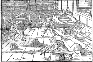 Ein schwarz-weißes 18. Jahrhundert-Etching von drei Männern in traditioneller Kleidung, die in einer Fabrik arbeiten, mit einer Wand im Hintergrund und Text unten, der "18. Jahrhundert-Etching des Inneren einer Fabrik" lautet.