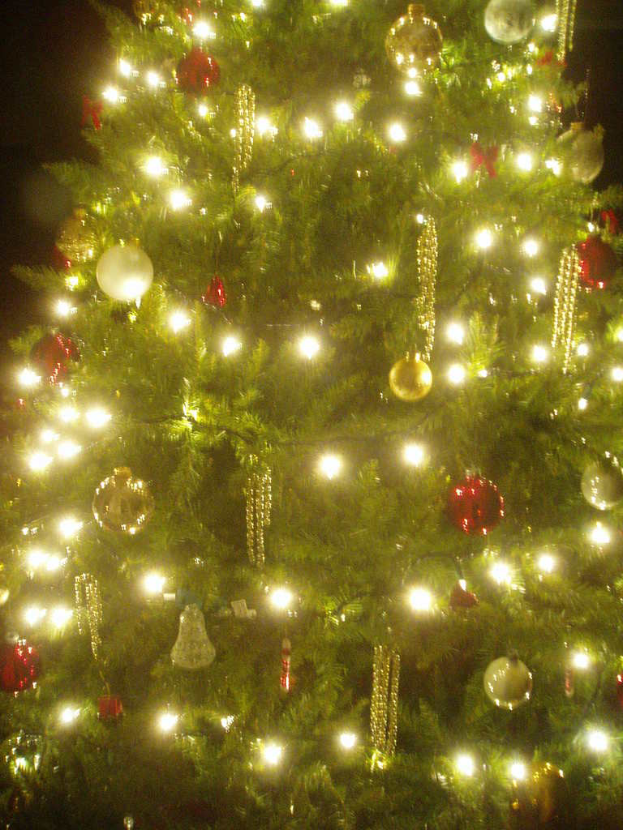 Ein Weihnachtsbaum mit Lichtern, Schmuck und anderen Verzierungen.