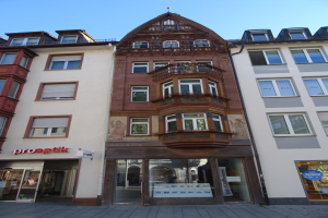 Ein Geschäftsgebäude mit zahlreichen Fenstern an der Seite, das sich auf einer Straße in Heidelberg, Deutschland befindet, unter einem klaren blauen Himmel.