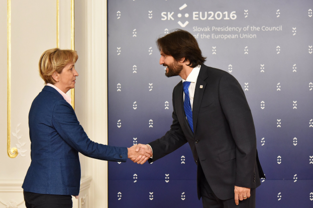 Bundeskanzlerin Angela Merkel und Bundespräsident Joachim Gauck schütteln sich die Hände vor einem Banner mit der Aufschrift "EU-Gipfel" mit einer Tür im Hintergrund, beide lächeln.