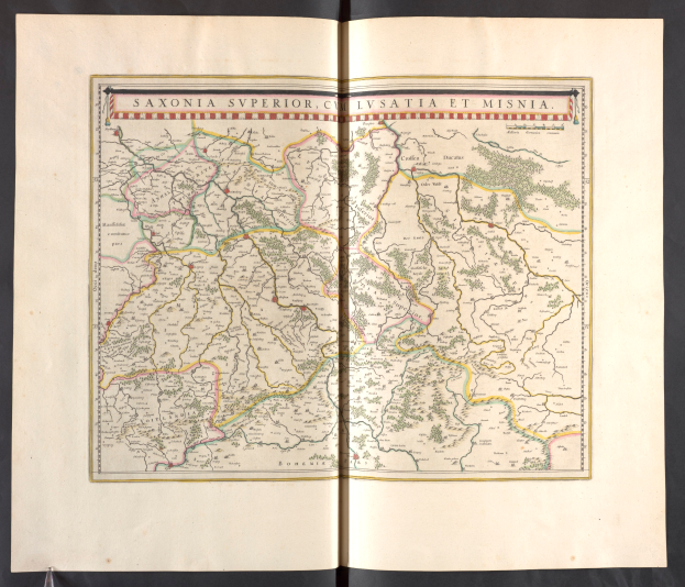 Ein aufgeschlagenes Buch mit einer detaillierten Karte von Sachsen, das die Provinzen und Städte hervorhebt, vor einem schwarzen Hintergrund.