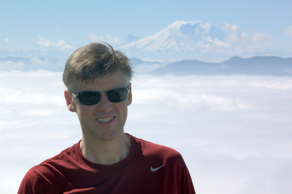 Ein Mann steht vor Eismassen und lächelt jemanden an.