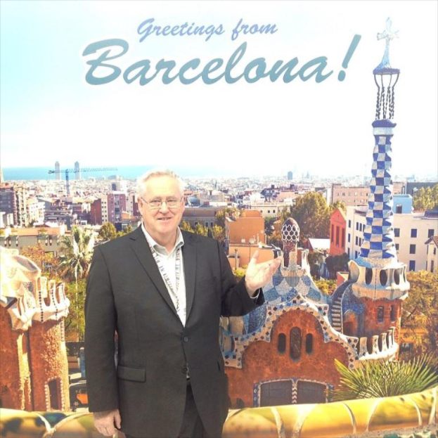 Ein Mann steht vor einem Plakat mit vielen Gebäuden und Türmen, über dem Plakat steht ein Grußtext.