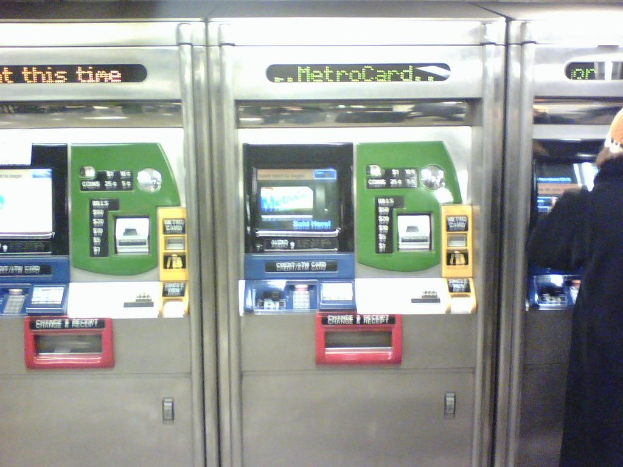 Automatische Fahrkartenverkaufsautomaten mit einer Person rechts daneben.