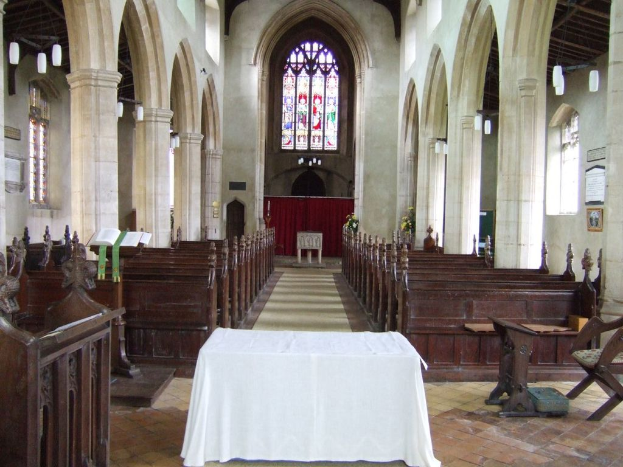 Ein Raum mit Tischen, einem Podium, einem Bücherstand, Stühlen, Bänken, Säulen, Tafeln, einem Vorhang, Fenstern, Stoff, Pflanzen und verschiedenen Gegenständen.