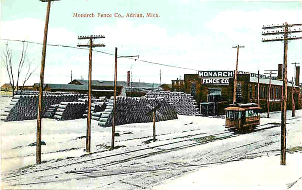 Eine schneebedeckte Landschaft mit einem Fahrzeug auf einer Spur, umgeben von Pfählen, mit einer Sammlung von Gegenständen hinter den Pfählen und einem Fabrikgebäude im Vordergrund.