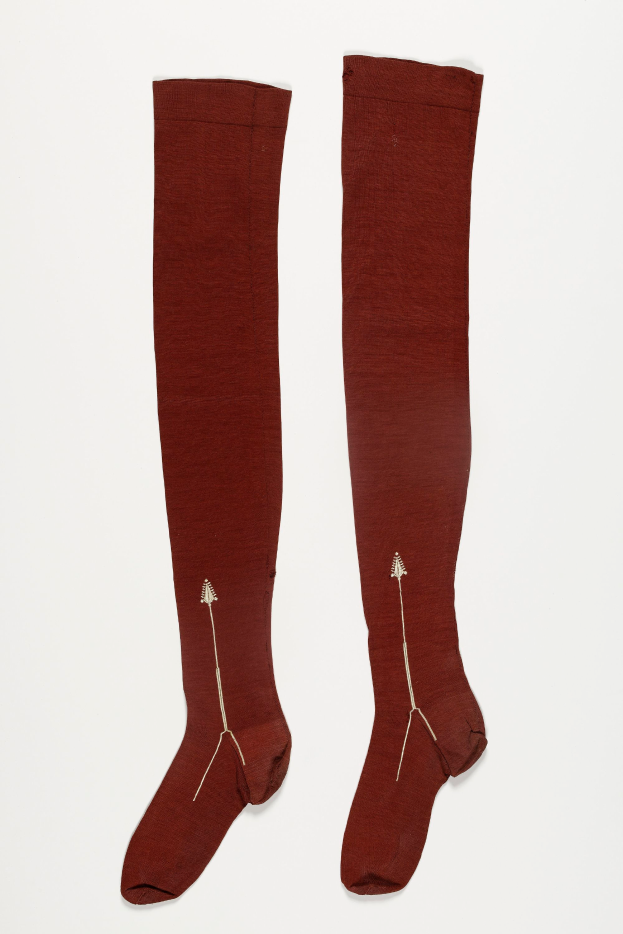 Ein Paar braune Kniestrümpfe mit Pfeil Design auf einem weißen Hintergrund.