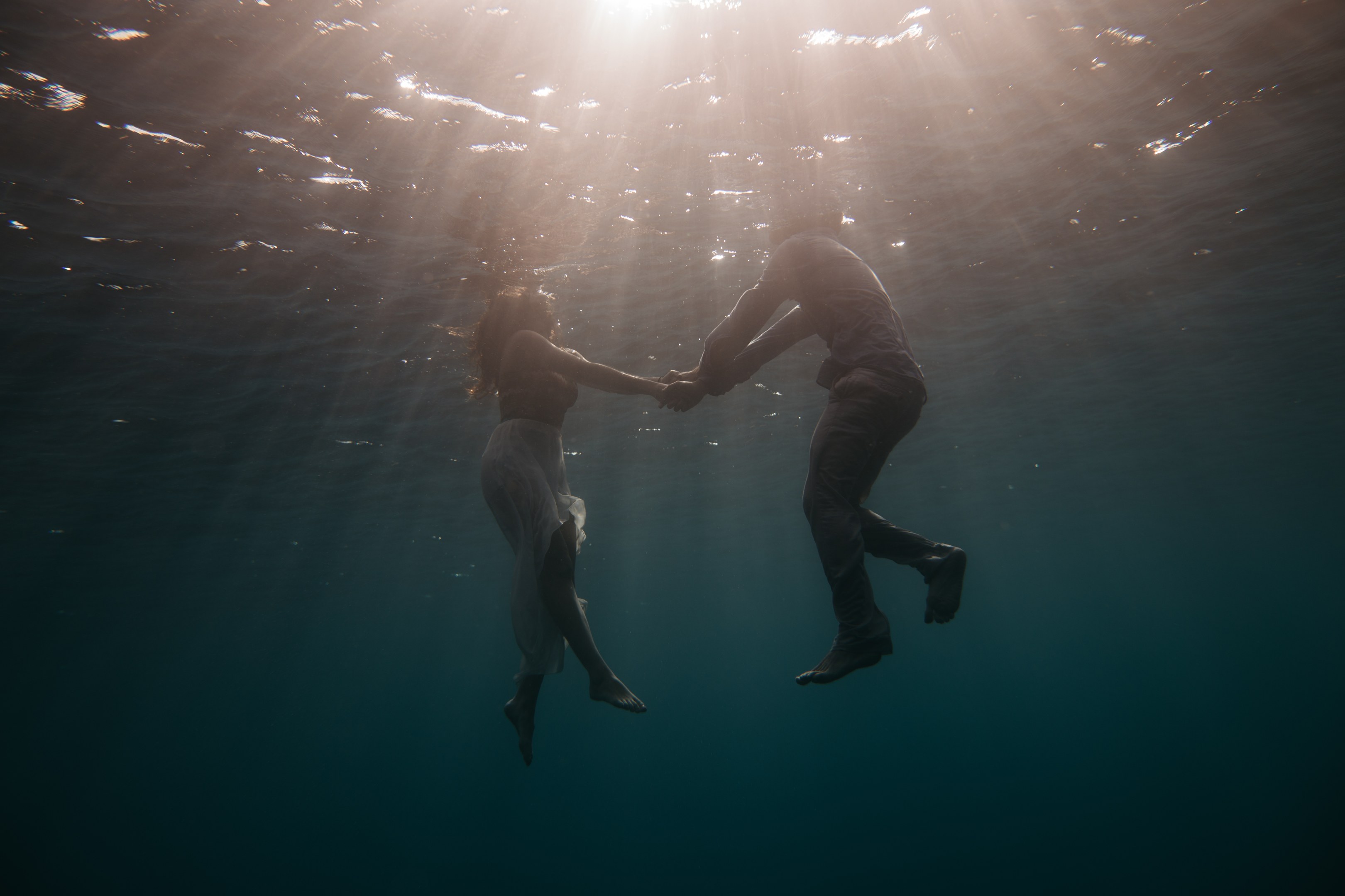 Zwei Personen, die sich unter Wasser in der Oceans mit Sonnenstrahlen halten