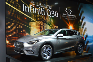 Ein schwarzer Infiniti Q30 mit Chromakzenten wird auf der IAA in Frankfurt gezeigt, im Hintergrund ein Banner mit Gebäuden und Lichtern.