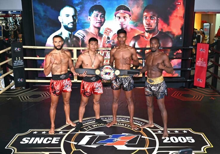Four men in a boxing ring hold championship belts while a "Muay Thai World Championship" screen displays behind them.
