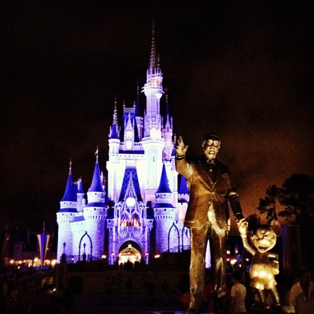 Statuen auf der rechten Seite, Cinderella-Schloss im Hintergrund, Bäume im Bild verteilt.