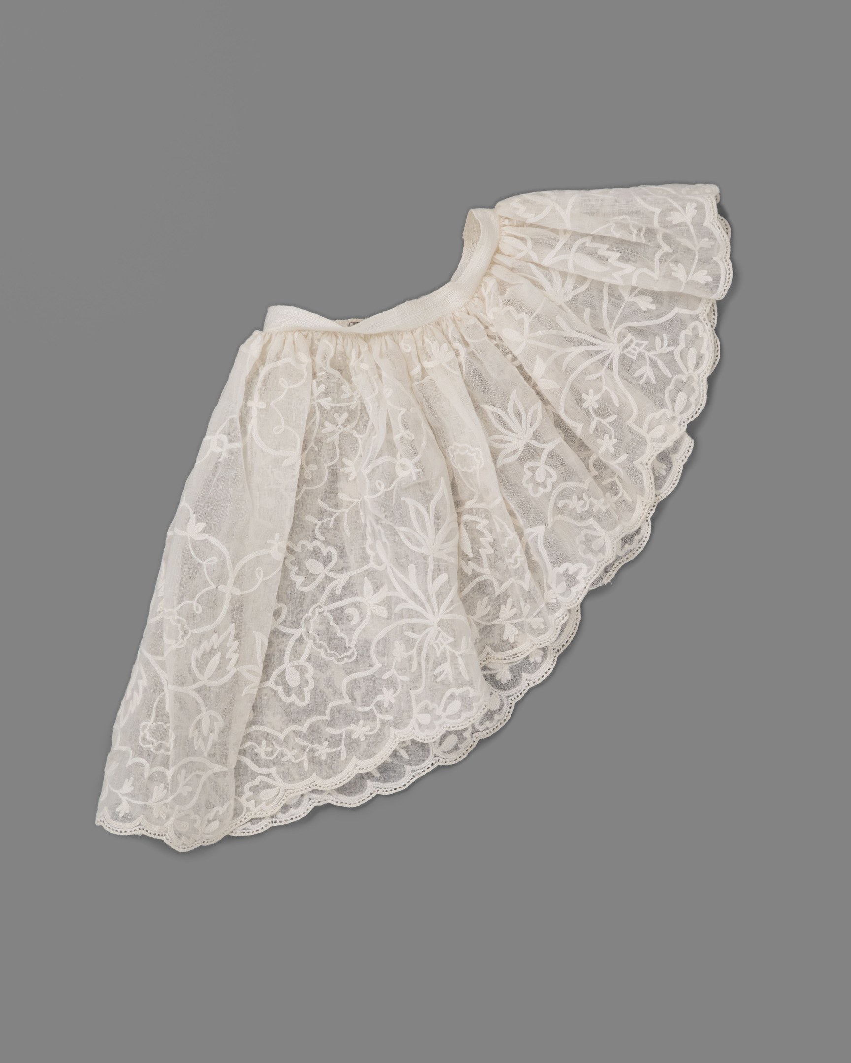 Weißer Rock mit zartem Spitzenüberzug auf grauem Hintergrund, mit leichtem Stoff und feiner, kleiner Stichmuster.