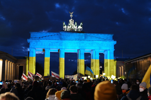 Menge mit Fahnen und Schildern vor dem Brandenburger Tor, mit einer Fahne auf der rechten Seite.