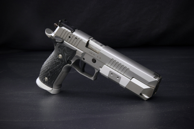 Sig Sauer P226 X-Five 9mm Pistole auf einer schwarzen Oberfläche mit einem schwarzen Hintergrund.