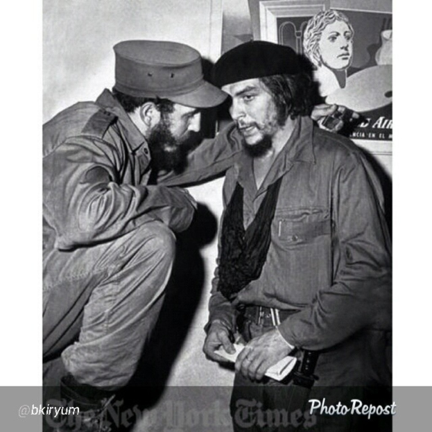 Zwei Personen unterhalten sich vor einem Rahmen und einer Wand, mit Text am unteren Bildrand.