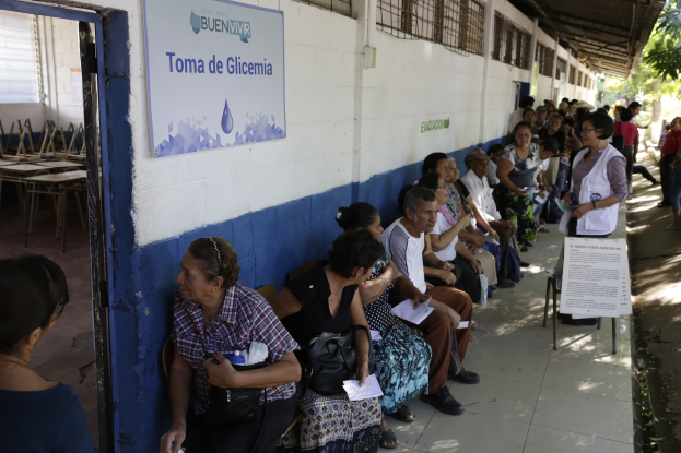 Menschen, die auf Bänken vor einem Gebäude sitzen und in einer Schlange vor einer Wahllokal in Guadalajara, Mexiko, warten