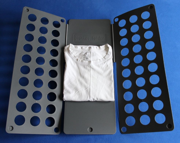 Weißes T-Shirt auf blauer Oberfläche neben einem schwarzen und aschgrauen Kleiderordner mit mehreren Löchern.