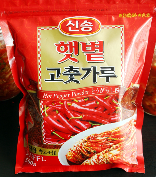 Ein rotes PÃ¤ckchen mit der Aufschrift "SchÃ¤rfepulver" und einem Bild von roten Chilischoten darauf.