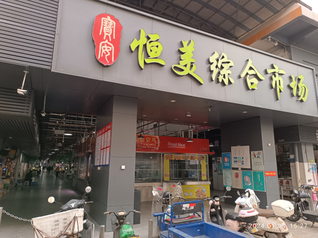 Außenansicht eines chinesischen Restaurants mit Schildern, umgeben von Motorrädern, Handwagen und urbanen Elementen, mit Menschen im Hintergrund unter einem sichtbaren Himmel.