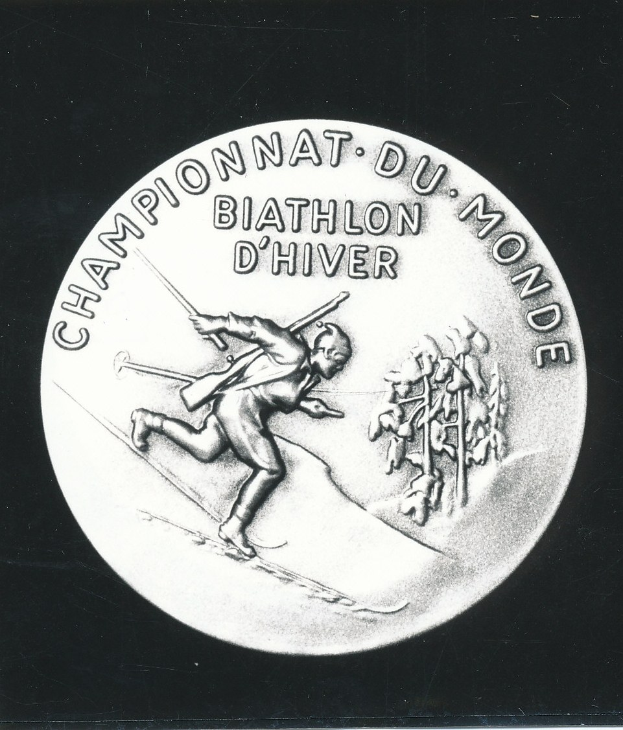 Silbermedaille mit eingraviertem Bild eines Skiläufers auf schwarzem Hintergrund mit eingravierter Schrift.