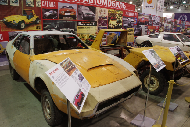 Ein Parkplatz mit mehreren Autos, Ständen mit Plakaten und einem großen Plakat im Hintergrund.