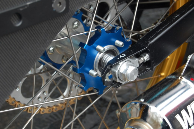 Ein Motorradrad und ein Schalldämpfer sind auf dem Bild zu sehen.