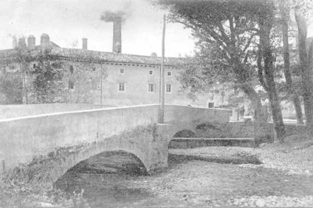 Eine Stadtansicht mit Gebäuden, Bäumen und einer Brücke im Vordergrund, Rauch der aus einem Schornstein aufsteigt, unter einem Himmel mit Wasser am Boden.