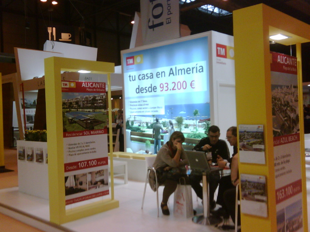 Ein Raum mit Menschen, die an einem Tisch arbeiten, umgeben von verschiedenen Flyern mit Werbung.