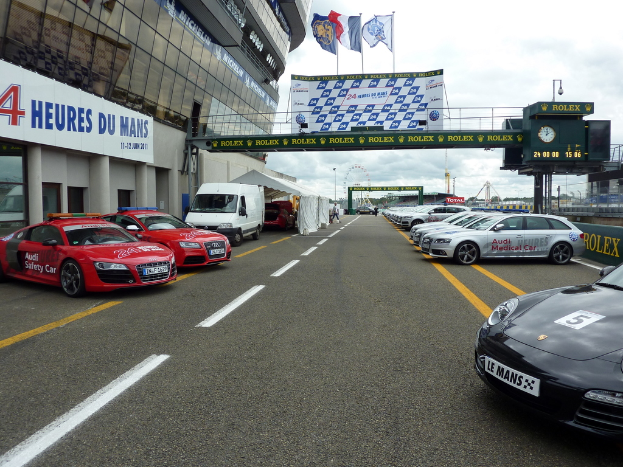 Autos parken vor einem Gebäude auf der rechten Seite, mit Schildern auf der rechten Seite.