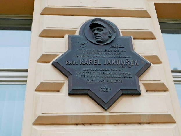 Plaque on a building featuring a portrait of a man in a hat, with text reading "Karel Janousek, the founder of the Soviet Union."