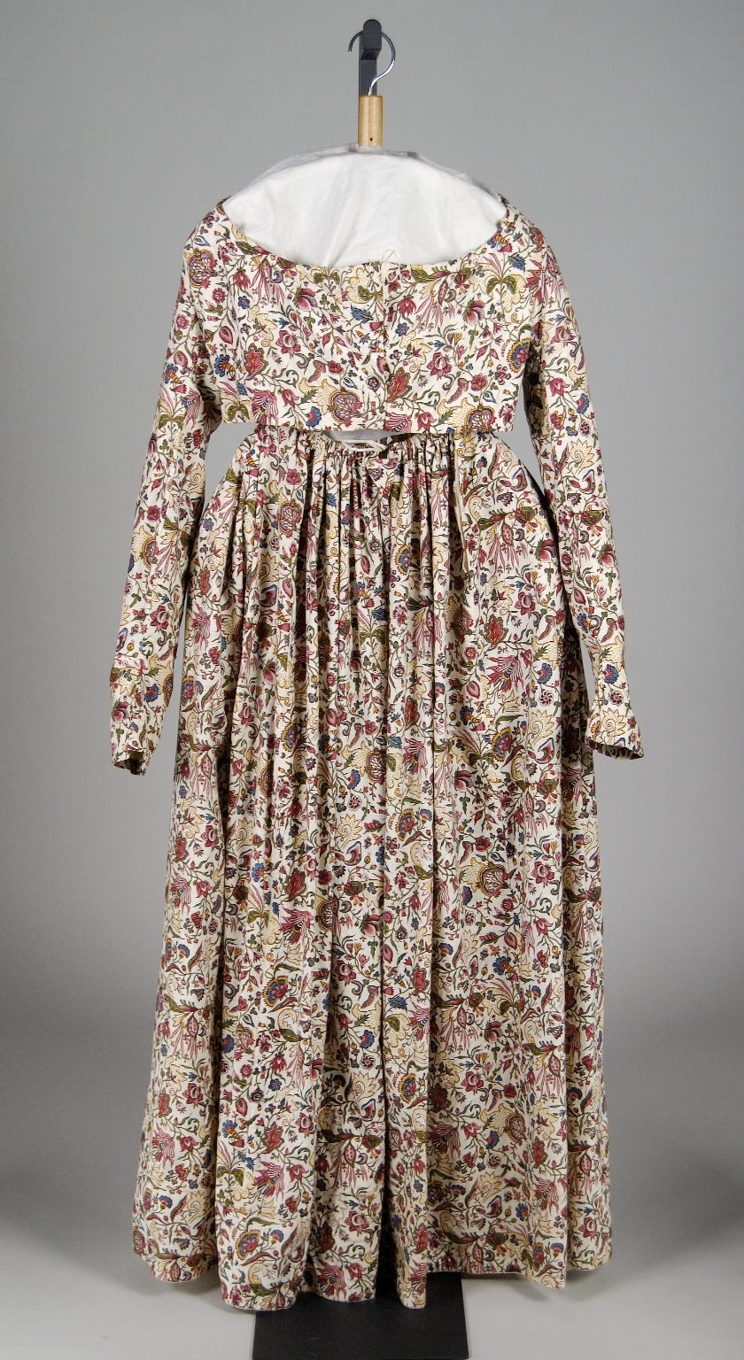 White floral-patterned dress with fitted bodice and floor-length full skirt, displayed on a hanger against a white background.
