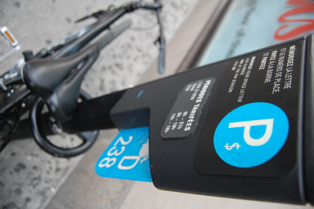 Ein Fahrrad steht auf dem Boden neben einem Parkautomaten, mit einem Gehweg am unteren Bildrand.