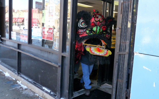 Eine Person in einem Kostüm steht auf dem Boden in einem Einkaufsbereich mit Geschäften, Infotafeln, Wänden und Boden.