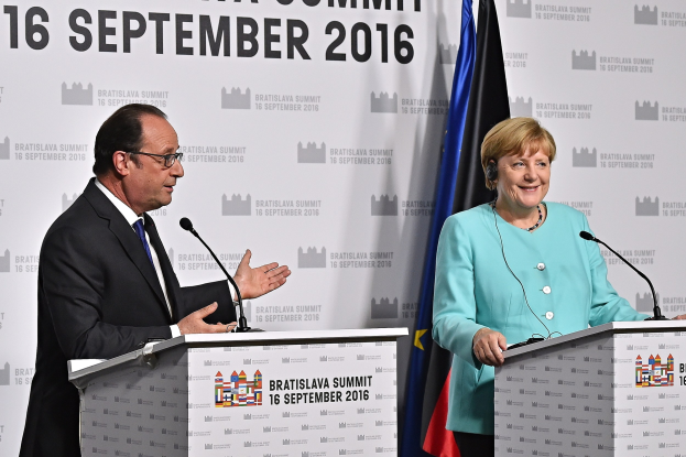 Two smiling leaders, Angela Merkel and François Hollande, stand at podiums with microphones, in front of a "Bratislava Summit 2016" banner.