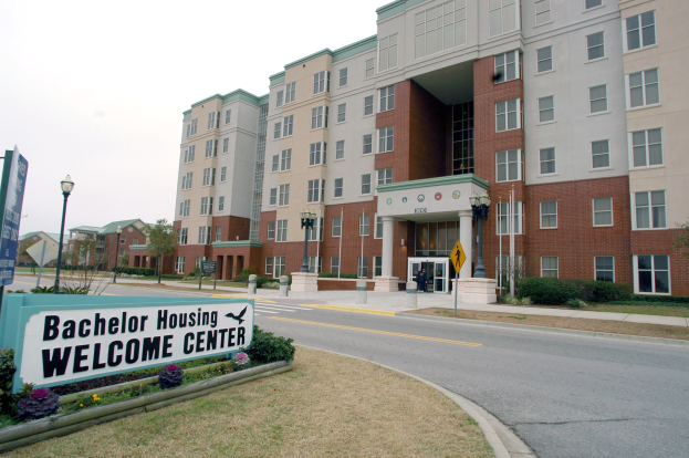 Willkommenszentrum für Bachelor-Wohnheime mit Gebäuden, Straßeninfrastruktur, Fahrzeugen, Grünflächen und einem klaren Himmel.